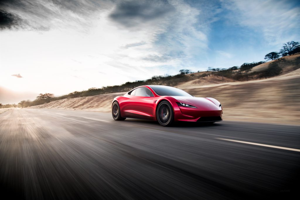En rød Tesla Roadster kjører på en vei